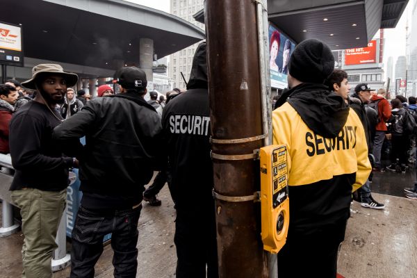 Unarmed security guards standing and observing a crowd.