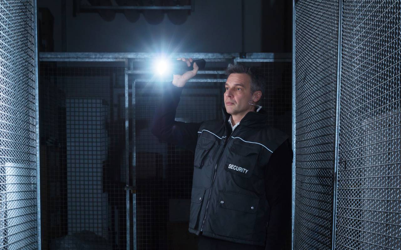 Security guard patrolling warehouse perimeter in Houston during nighttime